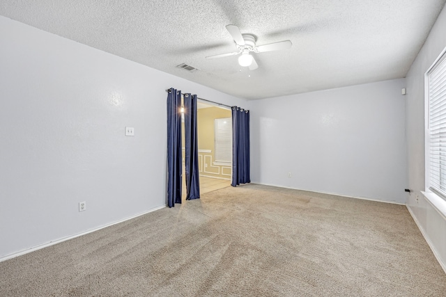 empty room with a textured ceiling, light colored carpet, and ceiling fan