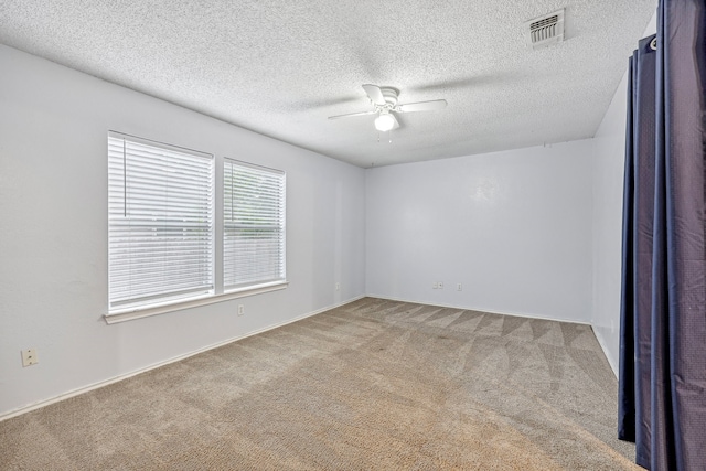 unfurnished room featuring a textured ceiling, light carpet, and ceiling fan