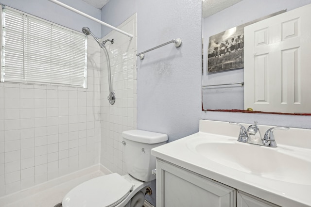 bathroom featuring tiled shower, vanity, and toilet