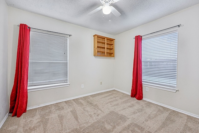 carpeted spare room featuring ceiling fan and a textured ceiling