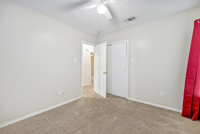 unfurnished bedroom featuring a textured ceiling, light colored carpet, and ceiling fan