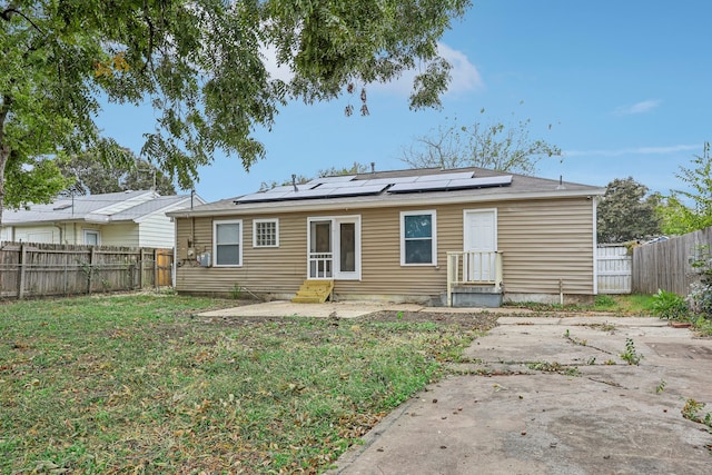 rear view of property with solar panels, a yard, and a patio area