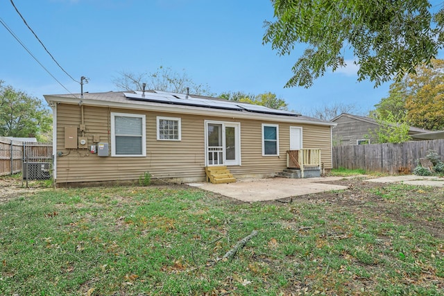 rear view of property featuring a patio, solar panels, and a lawn