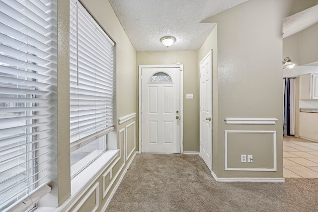 carpeted foyer entrance with a textured ceiling