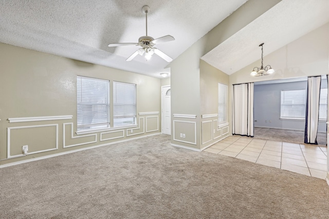 carpeted spare room with ceiling fan with notable chandelier, a textured ceiling, and vaulted ceiling