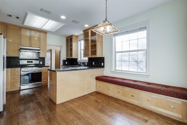 kitchen with backsplash, hanging light fixtures, kitchen peninsula, stainless steel gas range oven, and dark wood-type flooring