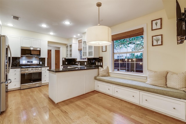 kitchen with white cabinetry, light wood-type flooring, kitchen peninsula, pendant lighting, and stainless steel appliances