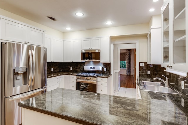 kitchen with dark stone countertops, sink, stainless steel appliances, and white cabinets