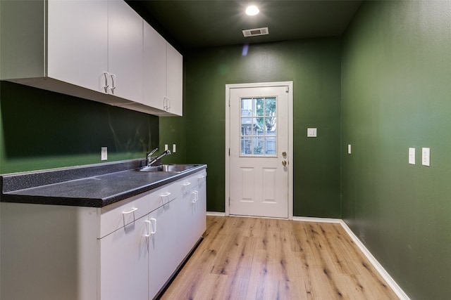 interior space with white cabinetry, sink, and light hardwood / wood-style flooring