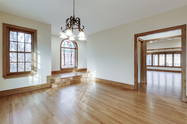 unfurnished dining area featuring light hardwood / wood-style floors and a notable chandelier