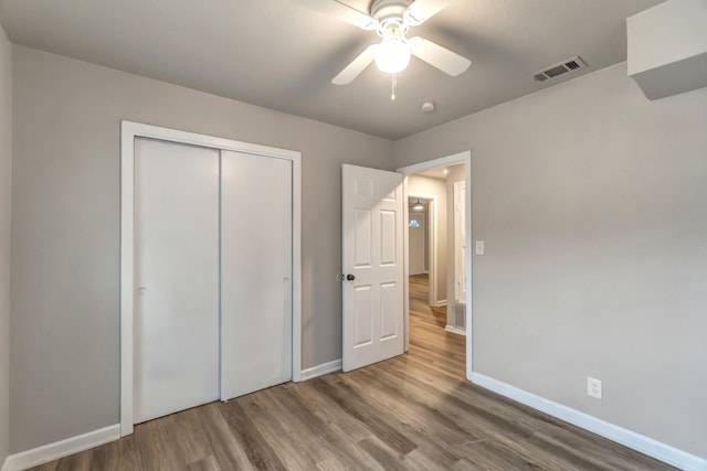 unfurnished bedroom with hardwood / wood-style floors, a closet, and ceiling fan