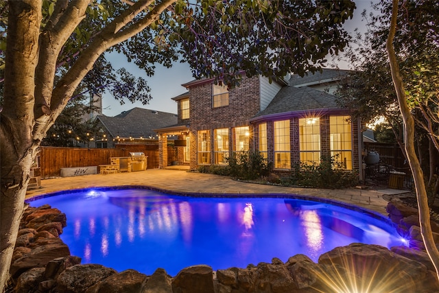 pool at dusk featuring a patio and area for grilling