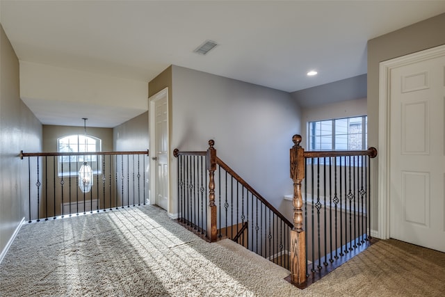 stairway with carpet and an inviting chandelier