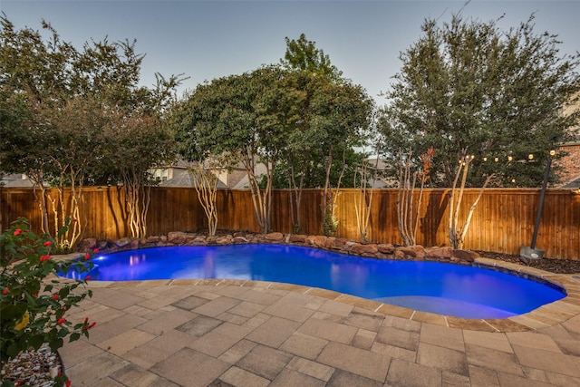 pool at dusk with a patio area