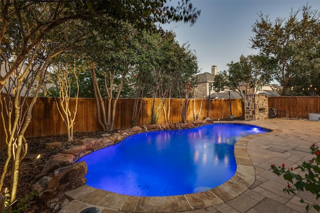 pool at dusk with a patio area