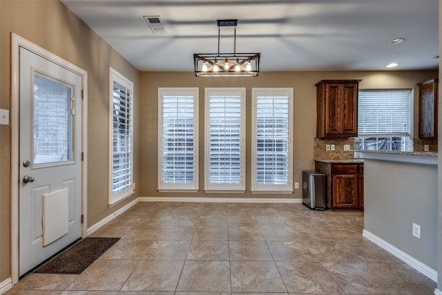 kitchen featuring backsplash, light stone counters, hanging light fixtures, and light tile patterned flooring