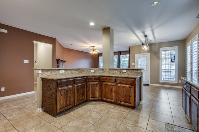 kitchen with a center island, light stone countertops, light tile patterned floors, and hanging light fixtures