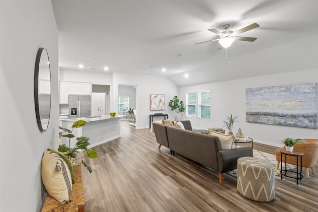 living room with sink, light hardwood / wood-style flooring, lofted ceiling, and ceiling fan