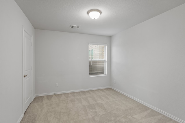 spare room with a textured ceiling and light colored carpet