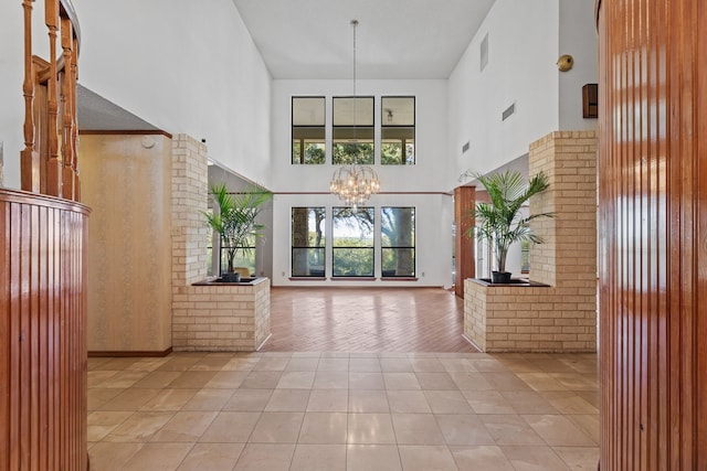 foyer featuring light hardwood / wood-style floors, a notable chandelier, and a towering ceiling