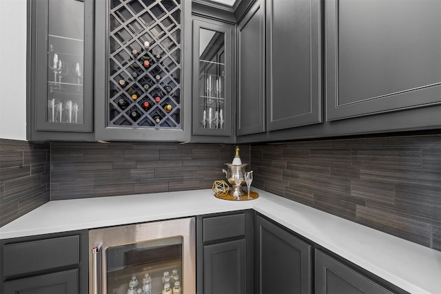 bar featuring tasteful backsplash, beverage cooler, and gray cabinetry