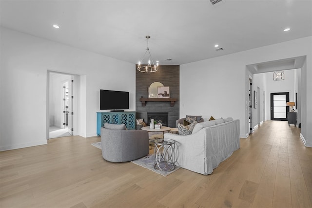 living room featuring light hardwood / wood-style flooring, a chandelier, and a fireplace