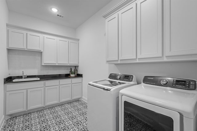 washroom with sink, washing machine and dryer, and cabinets