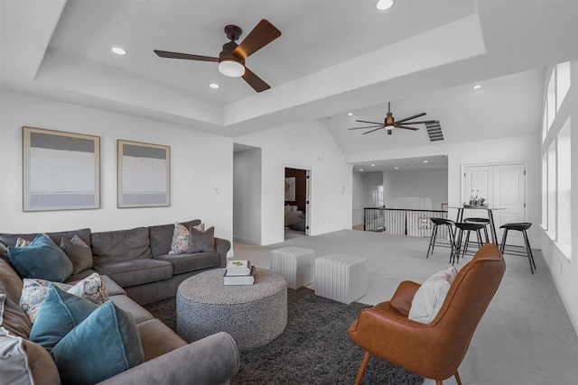 carpeted living room featuring ceiling fan, high vaulted ceiling, and a tray ceiling