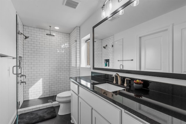 bathroom featuring vanity, toilet, walk in shower, and tile patterned flooring