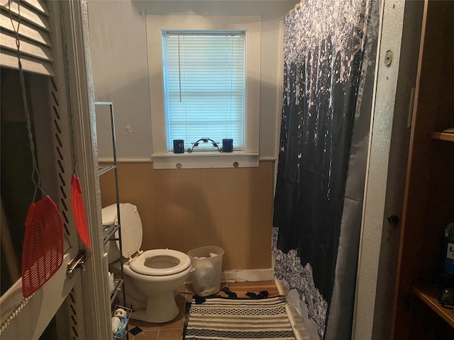 bathroom featuring tile patterned flooring, toilet, and curtained shower