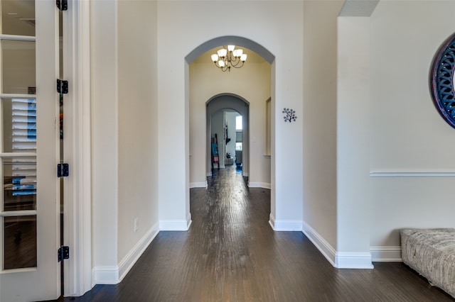 corridor with dark hardwood / wood-style flooring and an inviting chandelier