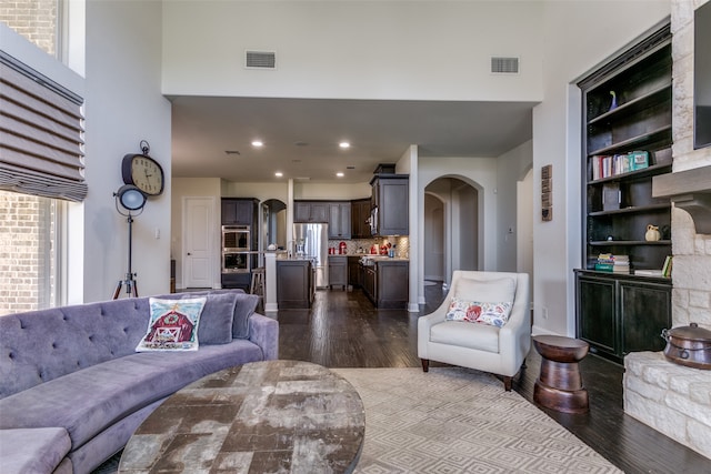 living room featuring a healthy amount of sunlight, a stone fireplace, light wood-type flooring, and built in features