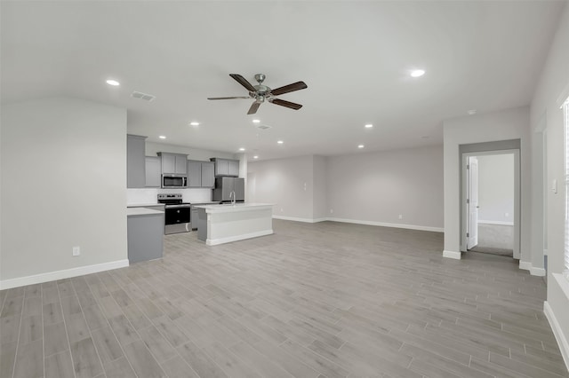 unfurnished living room featuring sink, light wood-type flooring, and ceiling fan