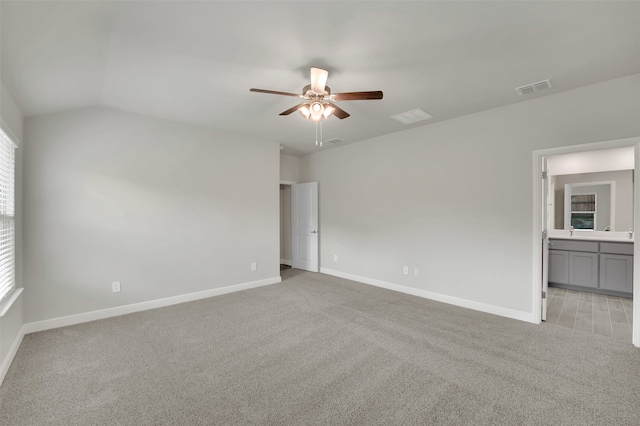 carpeted empty room featuring ceiling fan, vaulted ceiling, and plenty of natural light