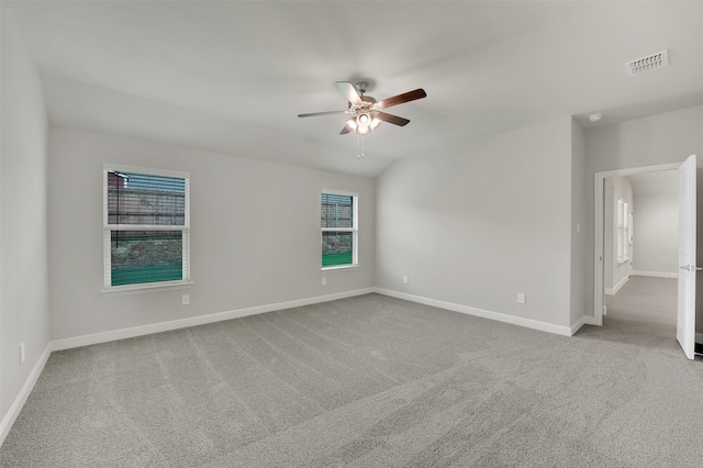 empty room with ceiling fan, a healthy amount of sunlight, and light colored carpet