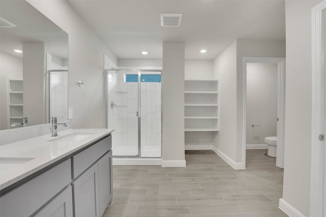 bathroom featuring vanity, a shower with shower door, hardwood / wood-style flooring, and toilet