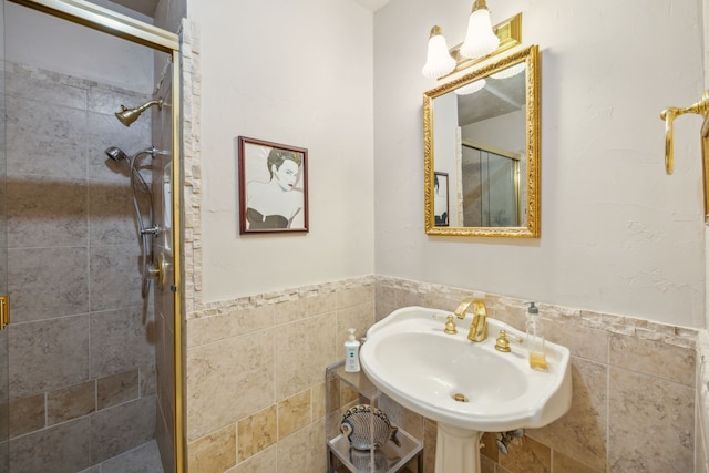 bathroom featuring a shower with door, tile walls, and sink