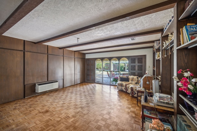 interior space featuring a wall mounted air conditioner, a textured ceiling, beam ceiling, and light parquet flooring