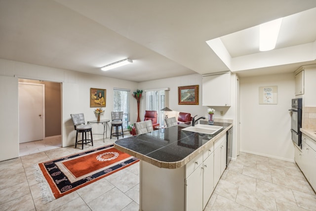 kitchen with stainless steel dishwasher, sink, white cabinets, and kitchen peninsula