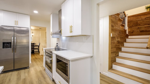 kitchen with white cabinetry, light hardwood / wood-style floors, stainless steel appliances, wall chimney exhaust hood, and exhaust hood