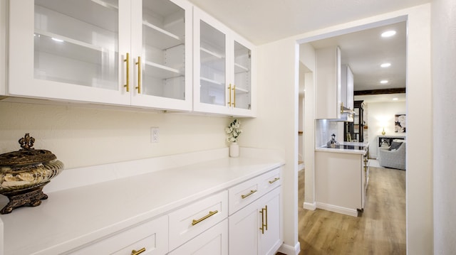 bar featuring light hardwood / wood-style floors and white cabinetry