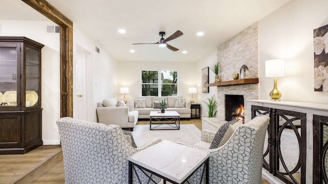 living room with a fireplace, light hardwood / wood-style floors, and ceiling fan