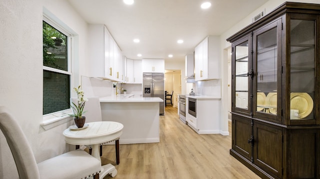 kitchen featuring light hardwood / wood-style floors, appliances with stainless steel finishes, kitchen peninsula, and white cabinets