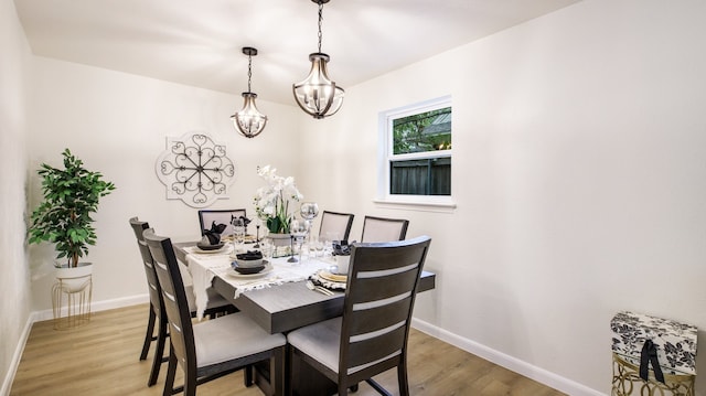 dining room with light hardwood / wood-style flooring and an inviting chandelier