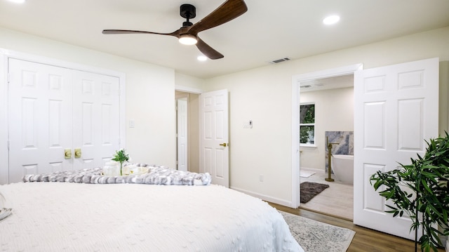 bedroom with connected bathroom, ceiling fan, and dark hardwood / wood-style flooring