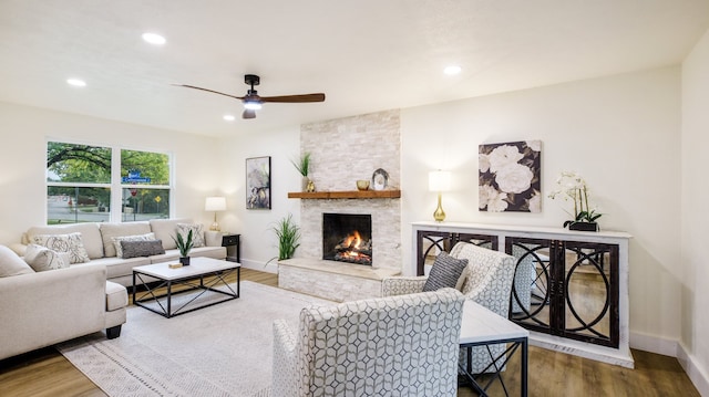 living room with a stone fireplace, hardwood / wood-style flooring, and ceiling fan