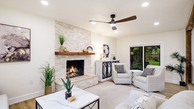 living room with ceiling fan, light wood-type flooring, and a fireplace