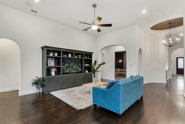 living room with a towering ceiling, dark hardwood / wood-style flooring, and ceiling fan with notable chandelier