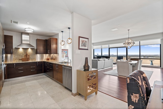 kitchen with a notable chandelier, a healthy amount of sunlight, wall chimney range hood, and dishwasher