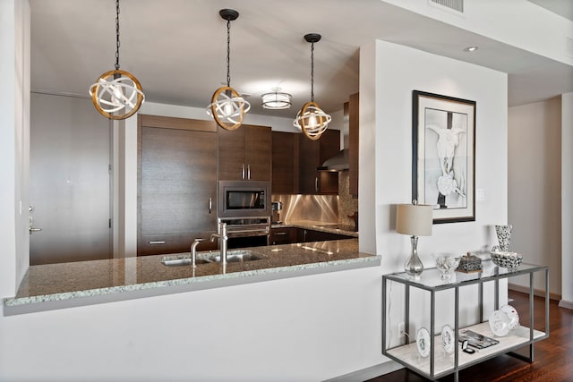 kitchen featuring kitchen peninsula, dark brown cabinetry, light stone counters, and stainless steel appliances